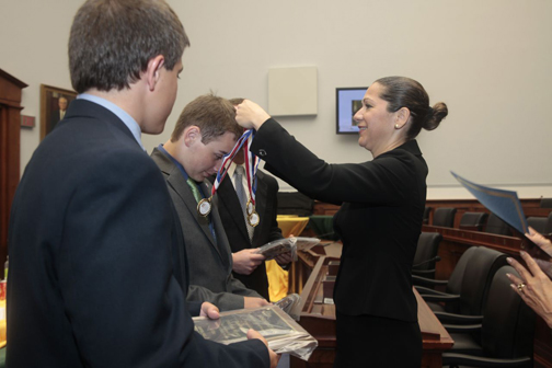 Melanie Mortimer, Executive Director for the SIFMA Foundation, presents students with medals